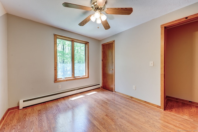 empty room featuring a baseboard heating unit, wood finished floors, ceiling fan, and baseboards