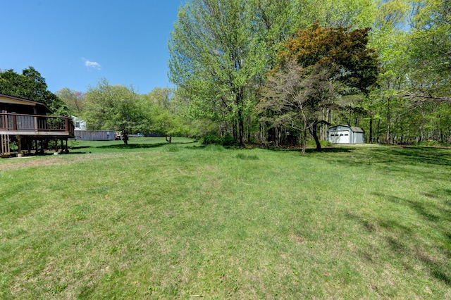view of green lawn with a storage shed, an outdoor structure, a garage, and a deck