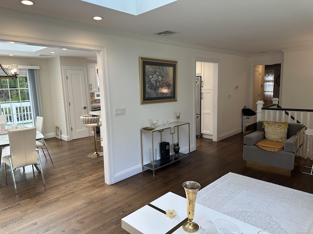 living area with a skylight, crown molding, dark wood finished floors, baseboards, and recessed lighting