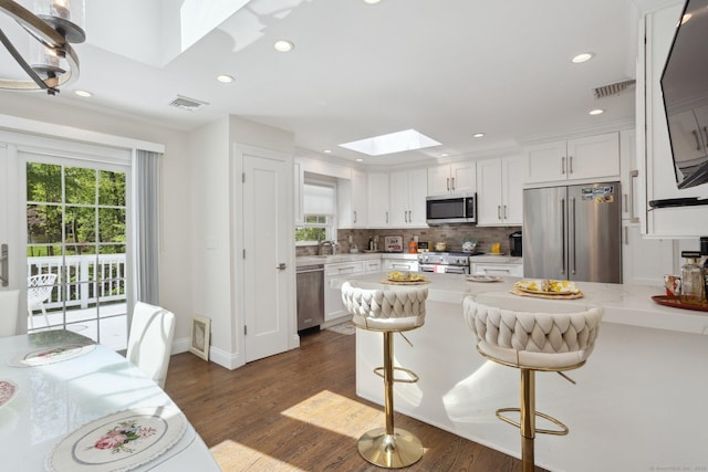 33 Pumpkin Hill Rd, Westport, CT 06880 - kitchen featuring high end appliances, a skylight, white cabinetry, dark wood-style flooring, and recessed lighting