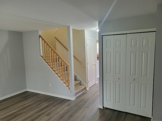 below grade area with dark wood-type flooring, stairs, and baseboards