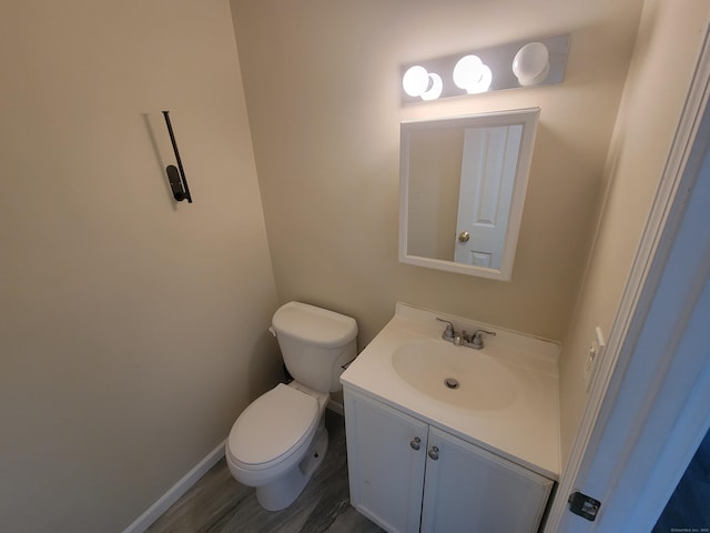 bathroom featuring toilet, vanity, wood finished floors, and baseboards