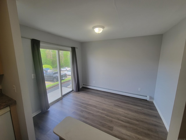 unfurnished dining area featuring a baseboard heating unit, dark wood-style flooring, and baseboards