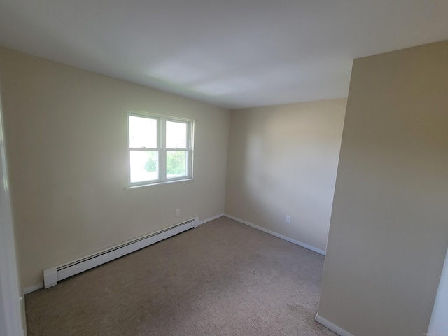 carpeted spare room with baseboard heating and baseboards