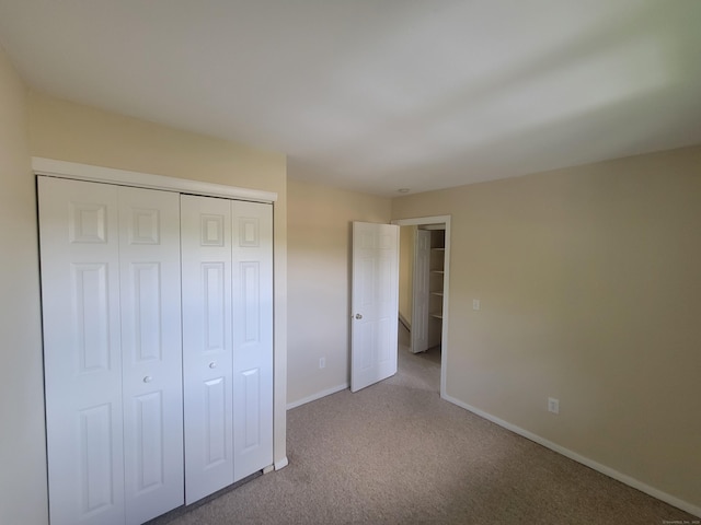 unfurnished bedroom featuring carpet floors, baseboards, and a closet