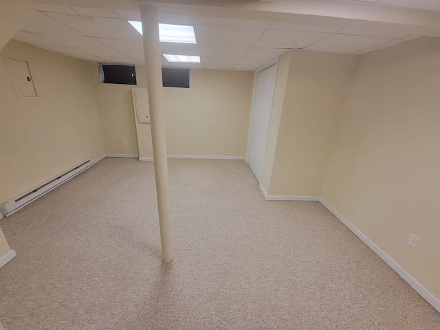 finished below grade area featuring a baseboard radiator, a drop ceiling, light colored carpet, and baseboards