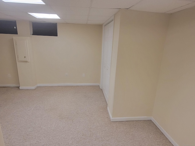 finished below grade area with a paneled ceiling, light colored carpet, and baseboards