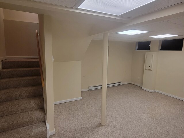 finished below grade area with a baseboard heating unit, carpet flooring, stairs, and baseboards