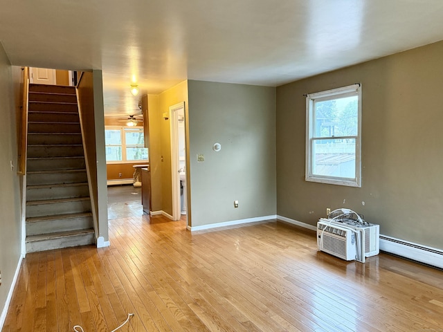 spare room with light wood-type flooring, stairs, baseboards, and baseboard heating