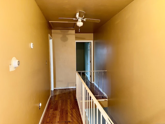 hall featuring an upstairs landing, attic access, wood finished floors, and baseboards