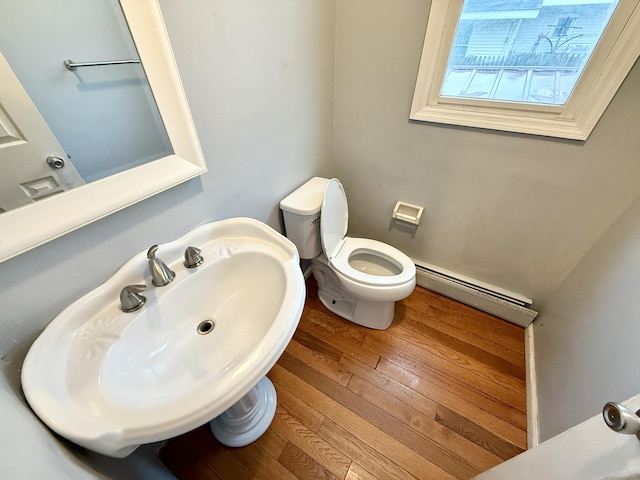 bathroom featuring baseboard heating, toilet, hardwood / wood-style floors, and a sink