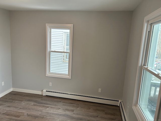 empty room featuring baseboard heating, wood finished floors, and baseboards