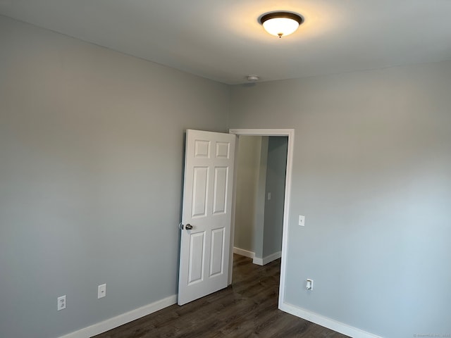 spare room featuring dark wood-style flooring, baseboards, and a smoke detector