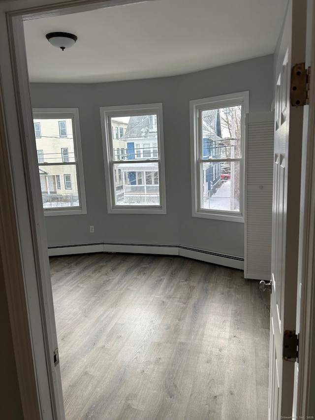 spare room featuring wood finished floors and a baseboard radiator