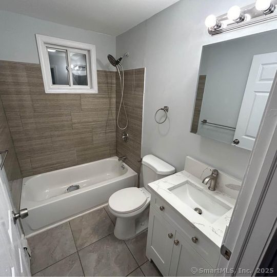 full bathroom with washtub / shower combination, tile patterned flooring, vanity, and toilet