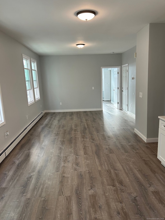 unfurnished room with dark wood-style floors, baseboards, and a baseboard radiator