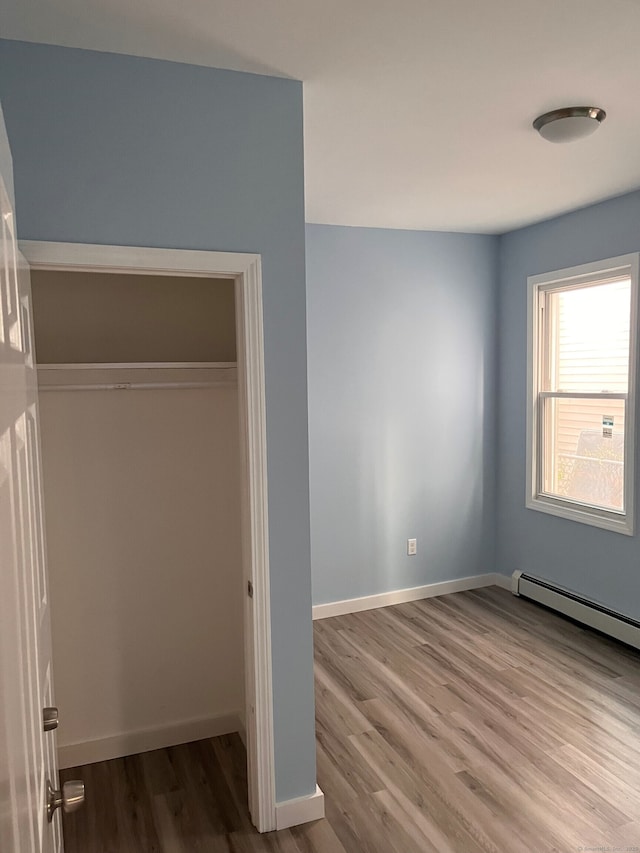 unfurnished bedroom with wood finished floors, baseboards, and a closet