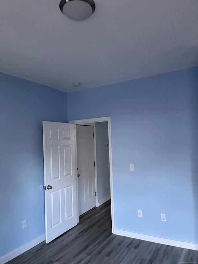 unfurnished room with baseboards and dark wood-style floors