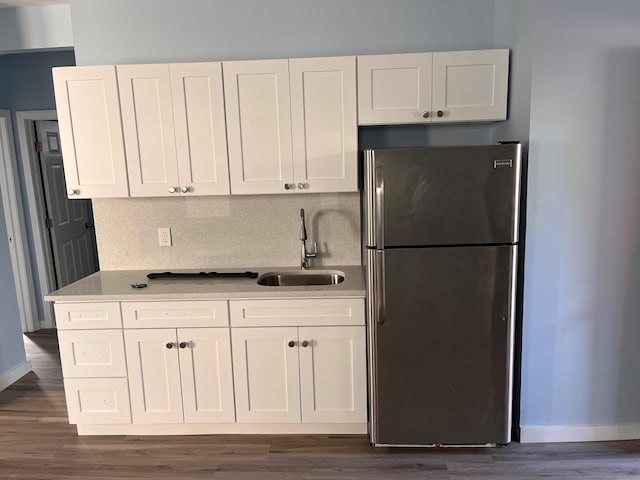 kitchen featuring freestanding refrigerator, a sink, white cabinetry, dark wood finished floors, and baseboards