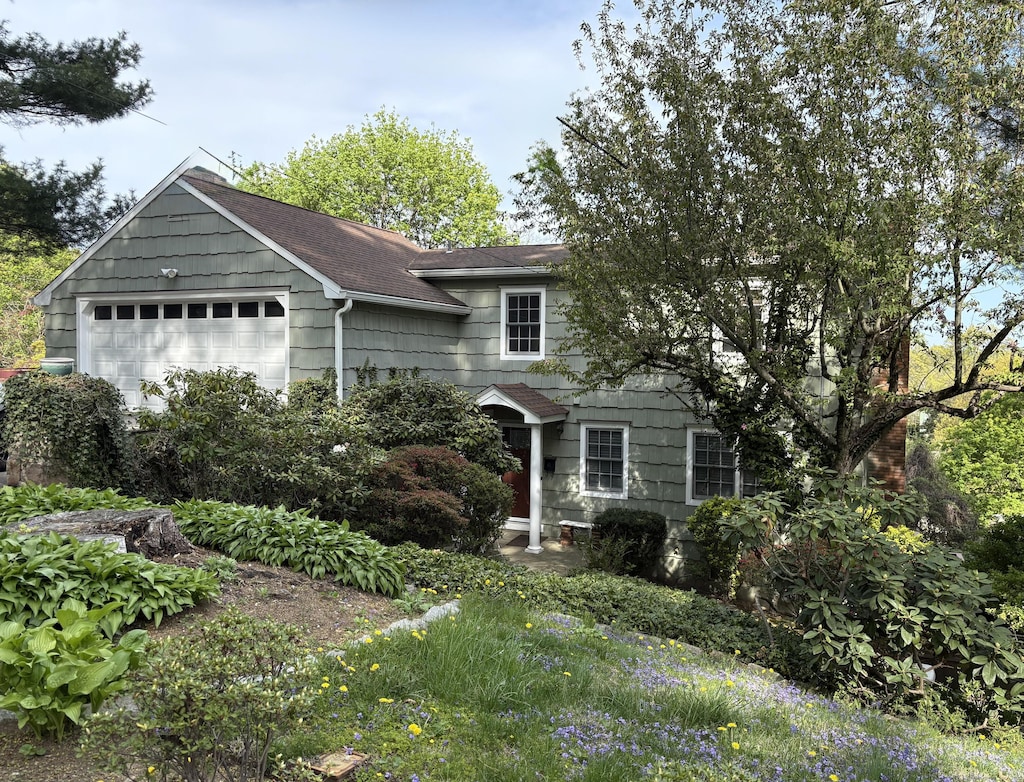 view of front of property featuring a garage and roof with shingles