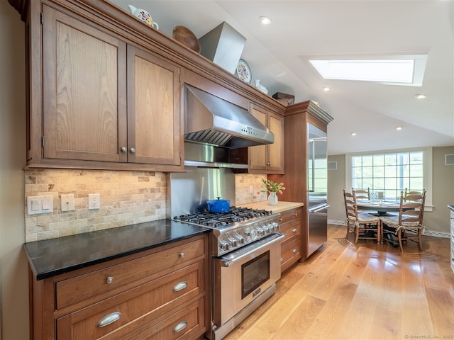 61 Nod Hill Rd, Wilton, CT 06897 - kitchen featuring high end appliances, wall chimney exhaust hood, a skylight, light wood finished floors, and brown cabinets
