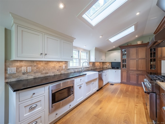 61 Nod Hill Rd, Wilton, CT 06897 - kitchen featuring appliances with stainless steel finishes, a skylight, a sink, dark countertops, and vaulted ceiling