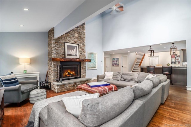 living room featuring stairs, a fireplace, wood finished floors, high vaulted ceiling, and recessed lighting