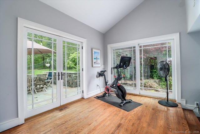 exercise room featuring french doors, wood finished floors, baseboards, and high vaulted ceiling