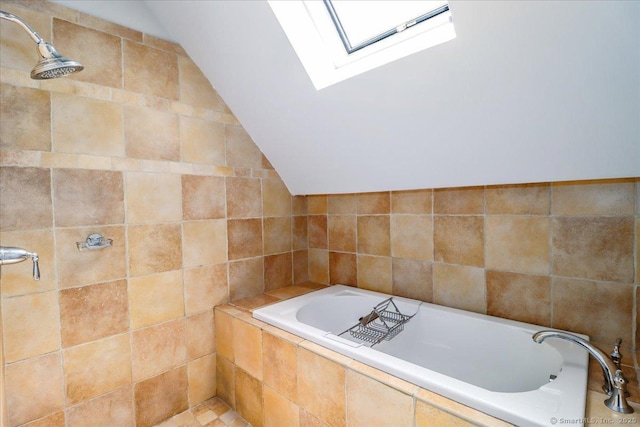 full bath with a skylight, vaulted ceiling, a garden tub, tile walls, and tiled shower