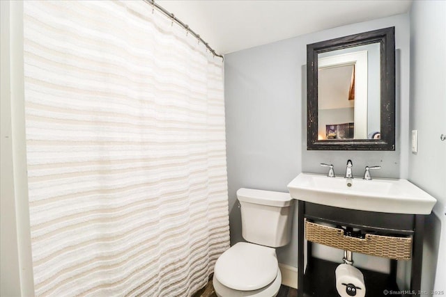 full bathroom with a sink, toilet, and curtained shower
