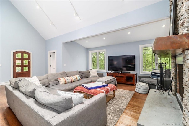 living area featuring lofted ceiling, wood finished floors, a fireplace, and recessed lighting