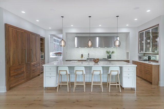 6 Spectacle Ln, Ridgefield, CT 06877 - kitchen featuring decorative backsplash, a kitchen breakfast bar, light wood-style flooring, recessed lighting, and brown cabinetry