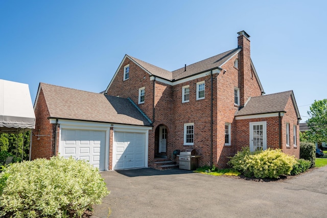 341 Quaker Ln N, West Hartford, CT 06119 - view of side of home with a chimney, brick siding, a garage, driveway, and a shingled roof