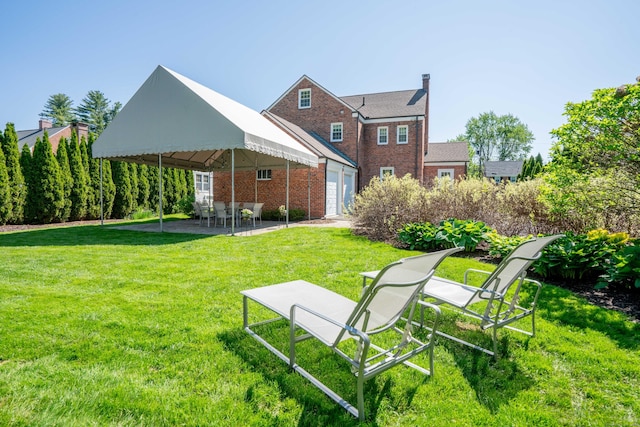 341 Quaker Ln N, West Hartford, CT 06119 - rear view of house featuring brick siding, a patio, and a yard