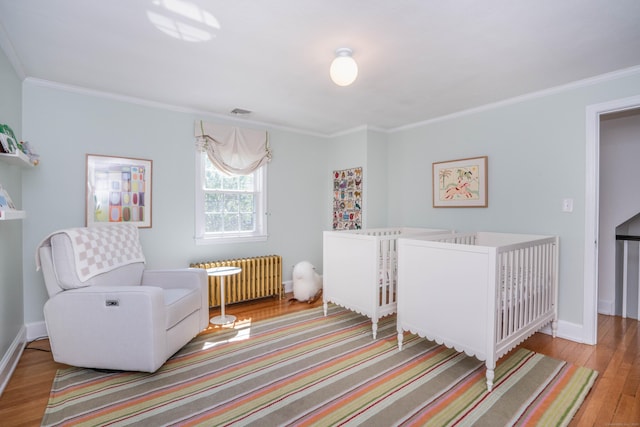 341 Quaker Ln N, West Hartford, CT 06119 - bedroom featuring radiator, wood finished floors, ornamental molding, baseboards, and a nursery area