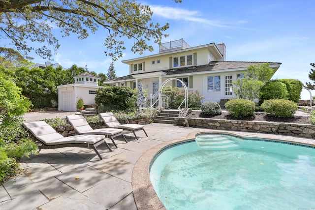 rear view of property featuring an outdoor pool, a patio area, and a chimney