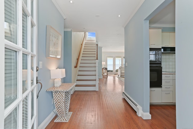 foyer entrance featuring baseboard heating, wood finished floors, stairway, ornamental molding, and recessed lighting