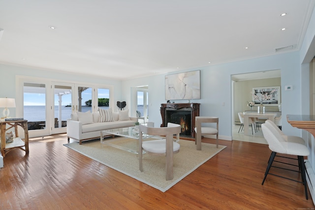 living room featuring french doors, a high end fireplace, crown molding, wood finished floors, and a baseboard radiator