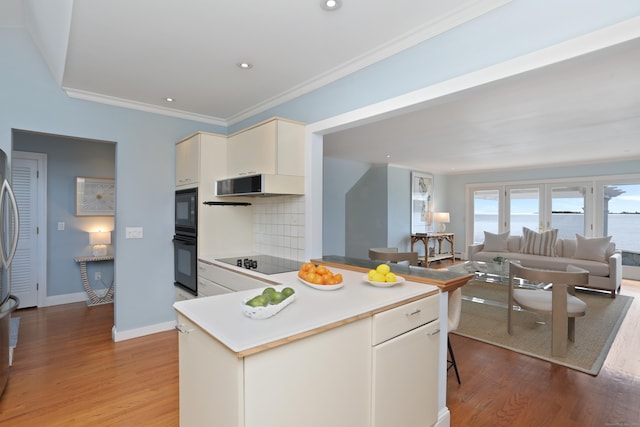 kitchen featuring black appliances, light wood-type flooring, ventilation hood, backsplash, and light countertops