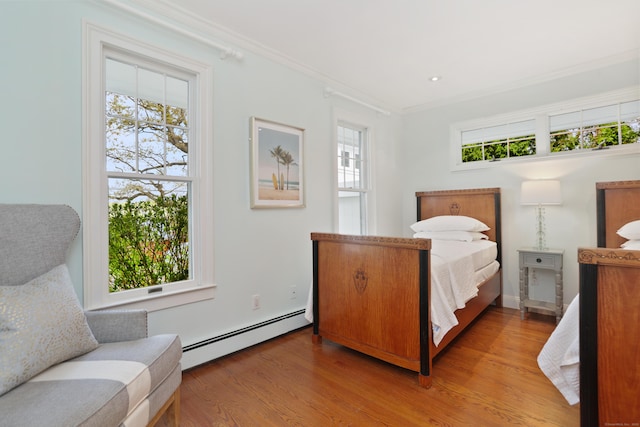bedroom with a baseboard heating unit, multiple windows, light wood-style flooring, and ornamental molding