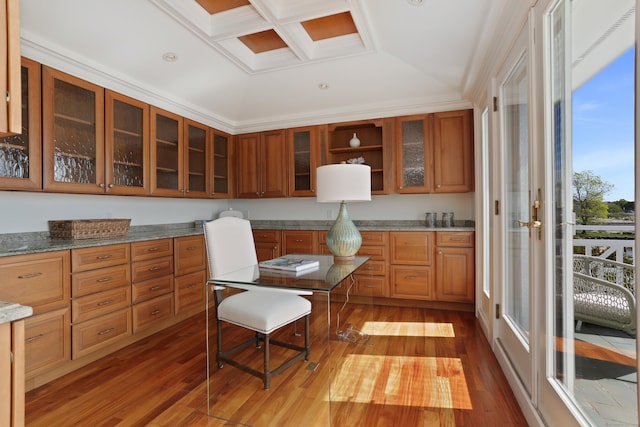 kitchen featuring wood-type flooring, brown cabinetry, glass insert cabinets, and coffered ceiling