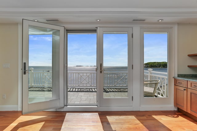 doorway to outside with wood finished floors, baseboards, crown molding, and recessed lighting