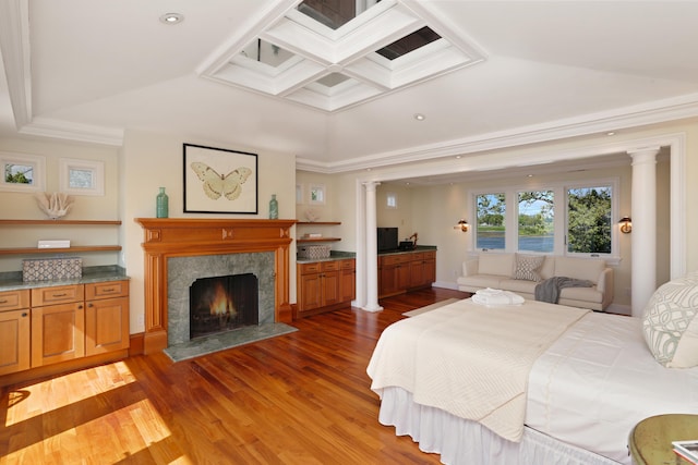 bedroom featuring decorative columns, ornamental molding, wood finished floors, a premium fireplace, and recessed lighting