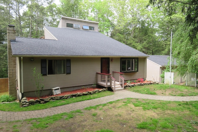 view of front of house with roof with shingles, a chimney, and a front lawn