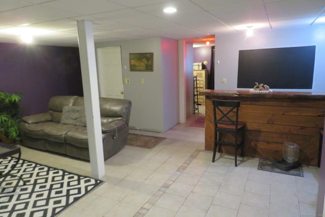 living area with a drop ceiling and a bar