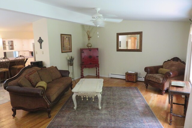 living area featuring baseboard heating, a ceiling fan, wood finished floors, and baseboards