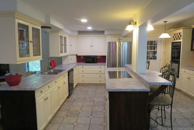 kitchen featuring black appliances, a kitchen breakfast bar, a center island, a sink, and glass insert cabinets