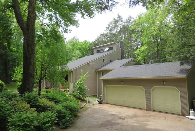 view of front of property with a garage, a chimney, driveway, and roof with shingles
