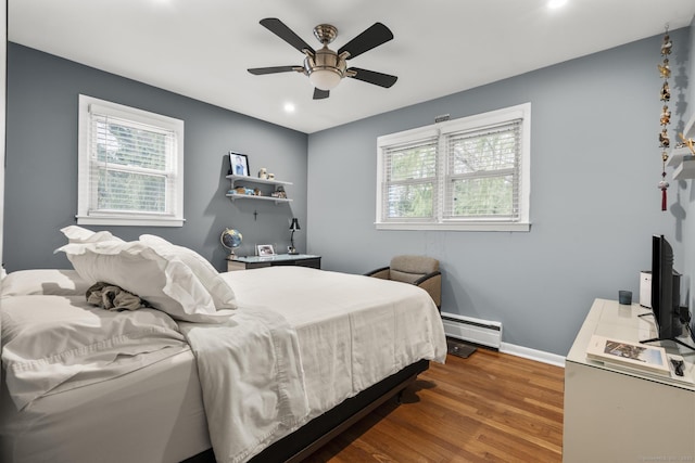 bedroom with a baseboard radiator, multiple windows, wood finished floors, recessed lighting, and baseboards