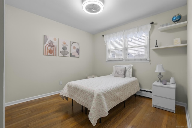 bedroom with baseboard heating, hardwood / wood-style floors, and baseboards